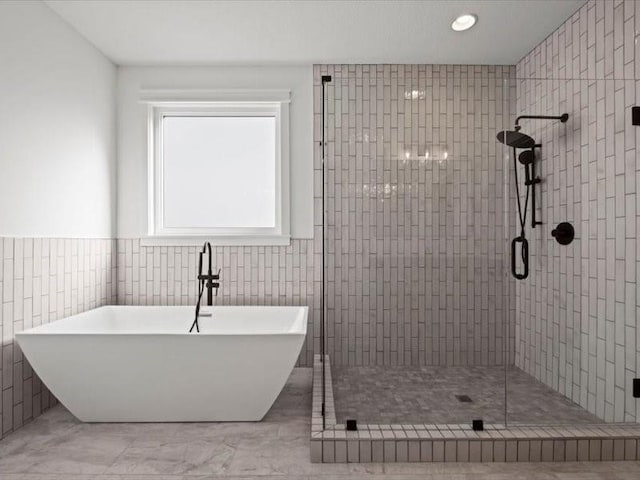 full bathroom with a freestanding bath, a stall shower, and tile walls