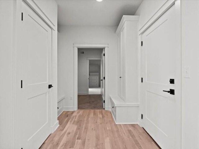 corridor with light wood-type flooring and baseboards