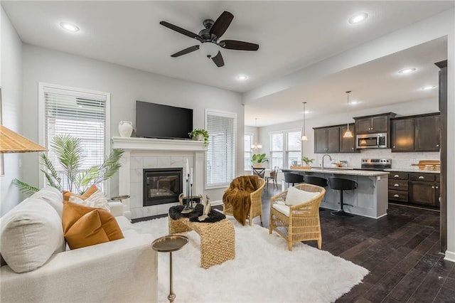 living room featuring dark wood-style floors, a tiled fireplace, and recessed lighting