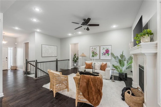 living area featuring baseboards, a glass covered fireplace, ceiling fan, wood finished floors, and recessed lighting