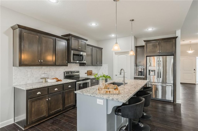 kitchen with a sink, dark brown cabinets, appliances with stainless steel finishes, backsplash, and dark wood finished floors