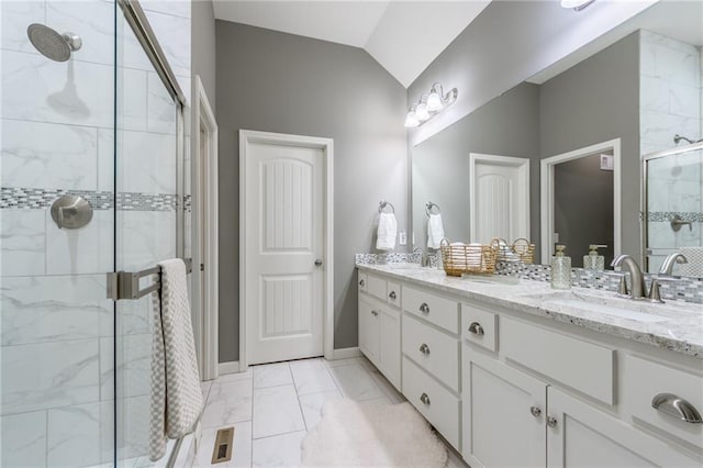 full bathroom with marble finish floor, double vanity, lofted ceiling, a sink, and a shower stall