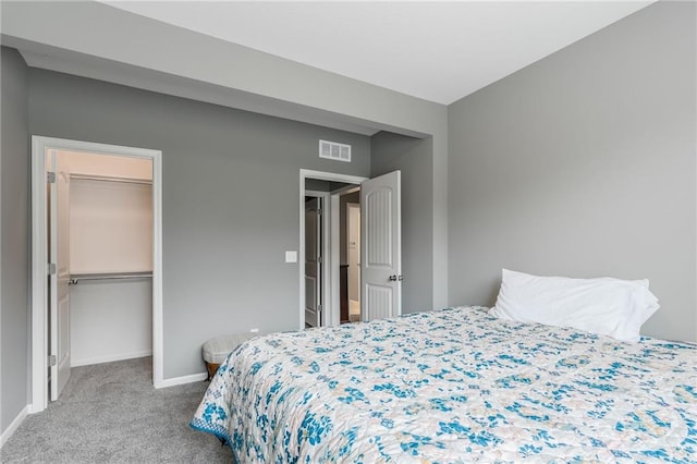 carpeted bedroom with baseboards, visible vents, a walk in closet, and a closet