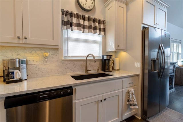 kitchen with sink, white cabinetry, stainless steel appliances, light stone countertops, and decorative backsplash