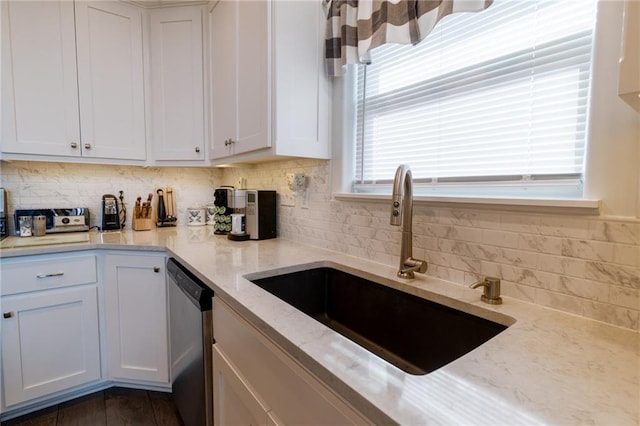 kitchen featuring light stone counters, sink, stainless steel dishwasher, and white cabinets