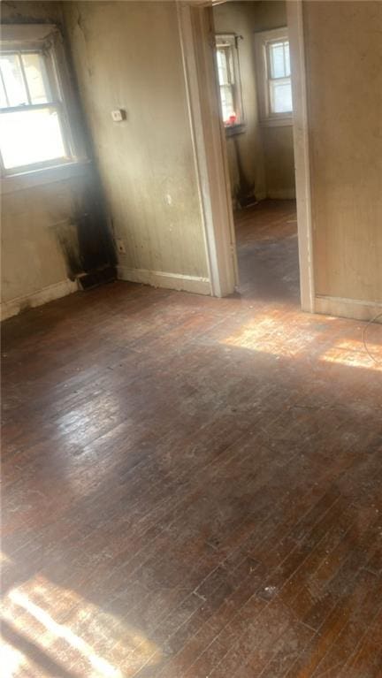 spare room with a wealth of natural light and dark hardwood / wood-style flooring