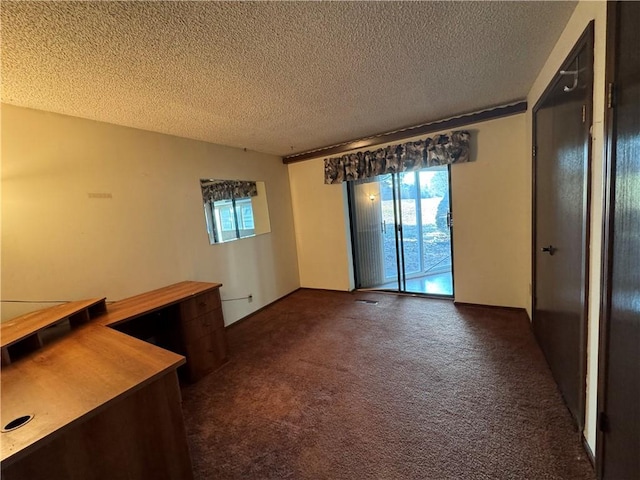 spare room with dark carpet, plenty of natural light, and a textured ceiling