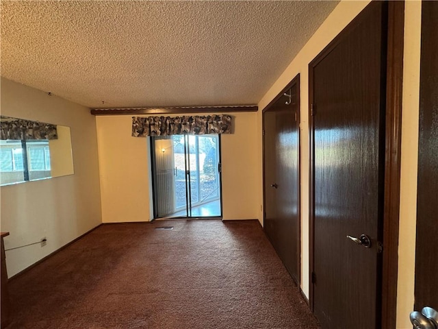 unfurnished room with dark colored carpet and a textured ceiling