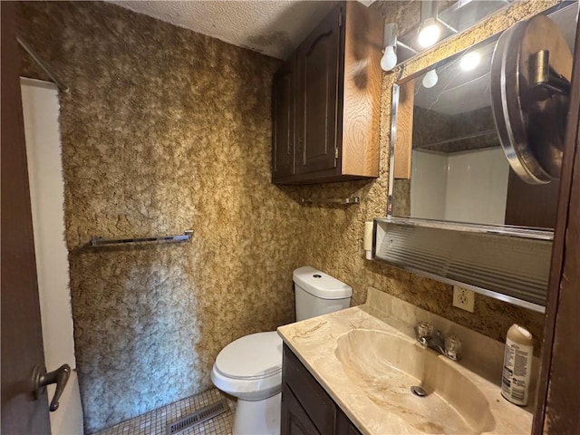 bathroom featuring vanity, a shower, a textured ceiling, and toilet