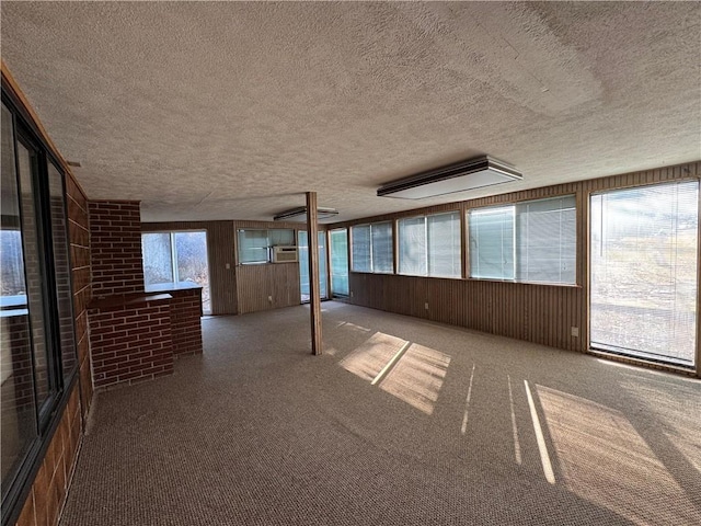 unfurnished room with carpet, a textured ceiling, and wood walls