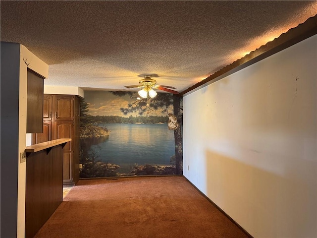 unfurnished dining area with ceiling fan, light carpet, and a textured ceiling