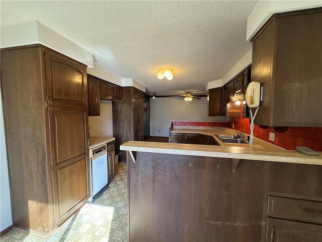 kitchen with ceiling fan, kitchen peninsula, sink, and dark brown cabinets