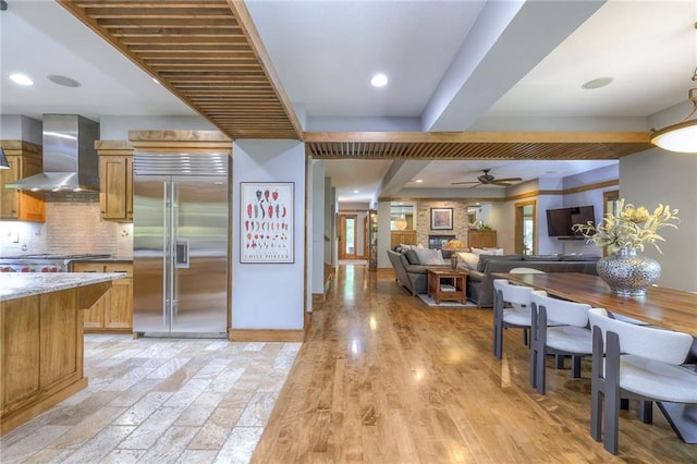 18402 W 64th St, Shawnee, KS 66218 - kitchen with appliances with stainless steel finishes, wall chimney exhaust hood, ceiling fan, brown cabinetry, and recessed lighting