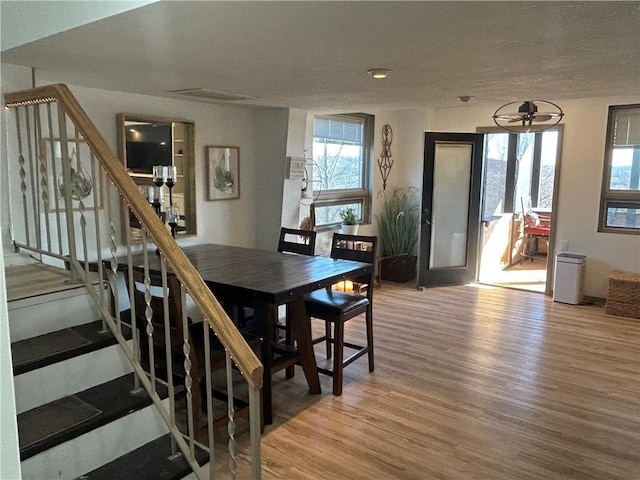 dining area with stairs, a textured ceiling, and wood finished floors