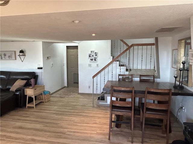 dining area with stairs, visible vents, and light wood finished floors