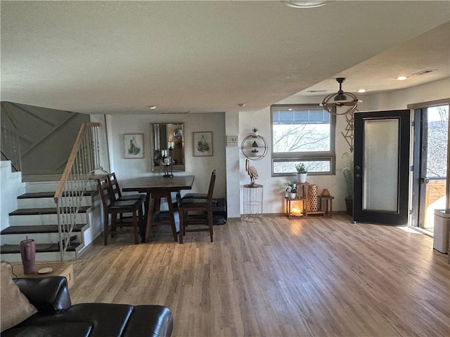 living area featuring stairs, a textured ceiling, baseboards, and wood finished floors