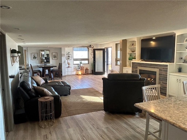 living area with a fireplace, light wood-type flooring, and a textured ceiling