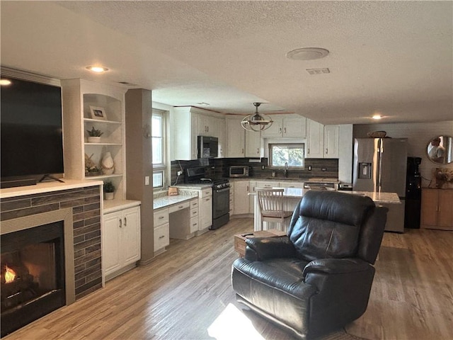 living area with a brick fireplace, a textured ceiling, and light wood-style flooring