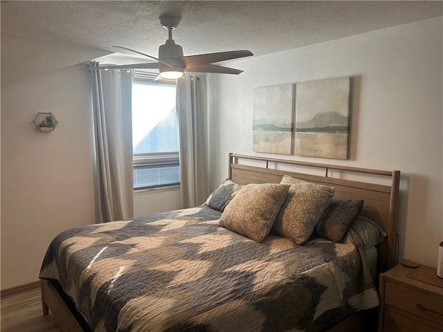 bedroom featuring a textured ceiling, ceiling fan, and wood finished floors