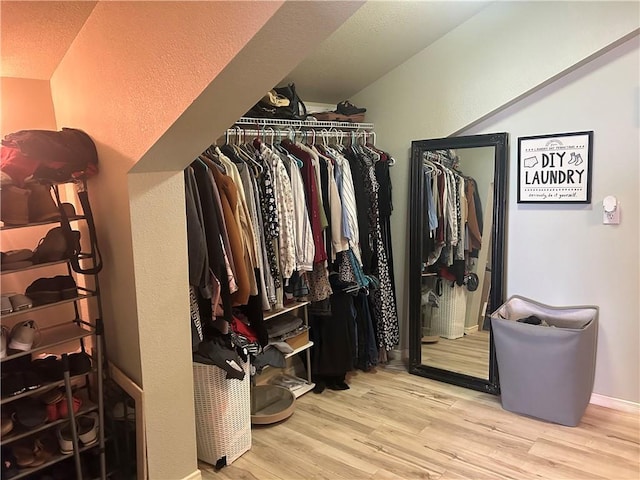 walk in closet with vaulted ceiling and light wood finished floors