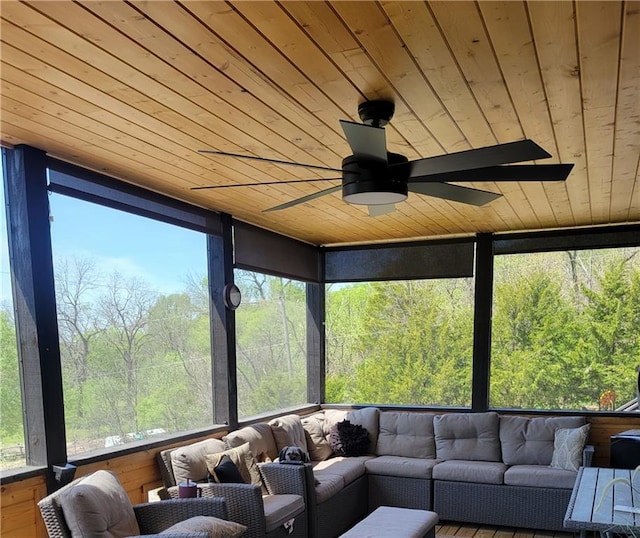 sunroom with a ceiling fan, a view of trees, and outdoor lounge area