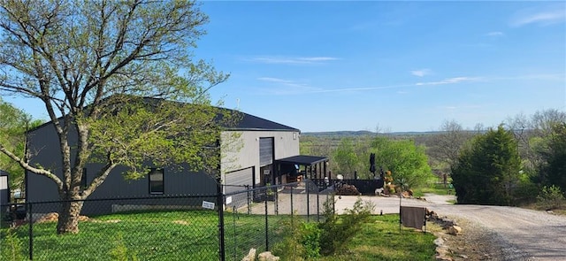 view of property exterior featuring a lawn, an attached garage, concrete driveway, and fence private yard