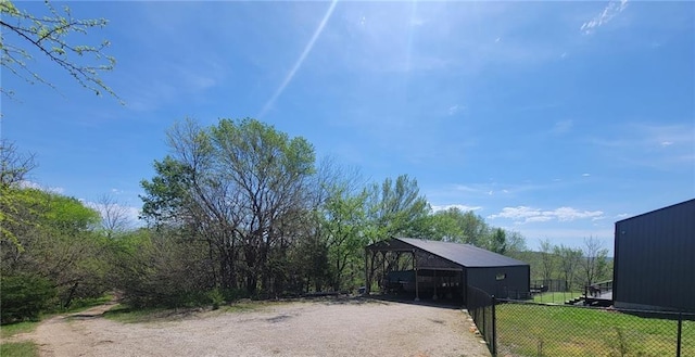 view of yard with a pole building, an outbuilding, fence, and driveway