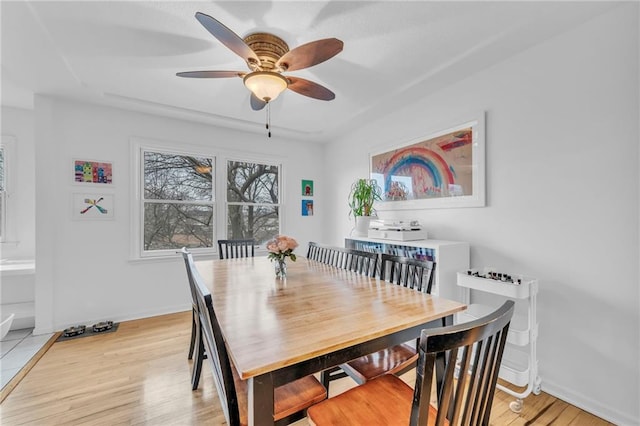 dining space with ceiling fan and light wood-type flooring