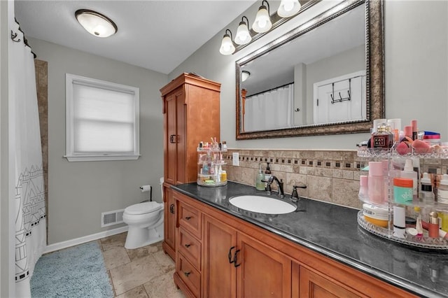 bathroom featuring tasteful backsplash, vanity, and toilet