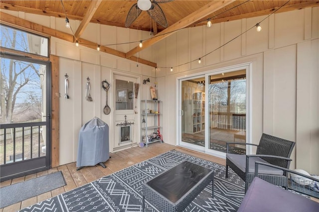 sunroom / solarium featuring ceiling fan, a healthy amount of sunlight, lofted ceiling with beams, and wooden ceiling