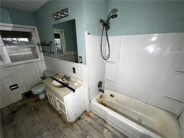 full bathroom with shower / bathtub combination, wood-type flooring, tile walls, vanity, and toilet