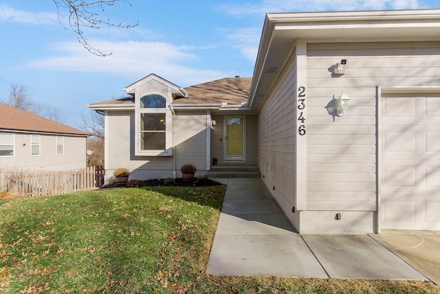 doorway to property featuring a garage and a lawn