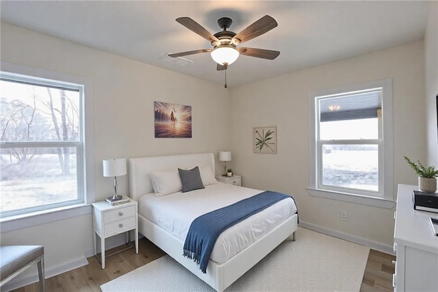 bedroom featuring ceiling fan, visible vents, baseboards, and wood finished floors