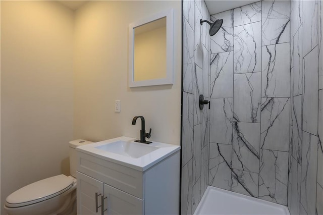 bathroom with vanity, a tile shower, and toilet