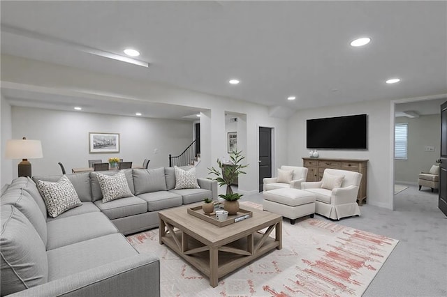 living room featuring light carpet, stairs, baseboards, and recessed lighting