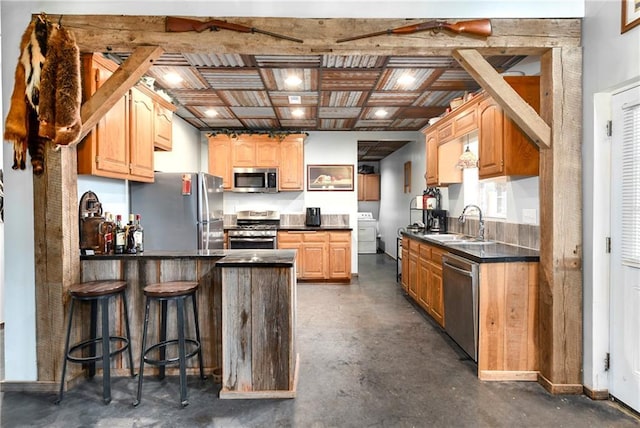 kitchen featuring a breakfast bar, sink, kitchen peninsula, stainless steel appliances, and washer / clothes dryer