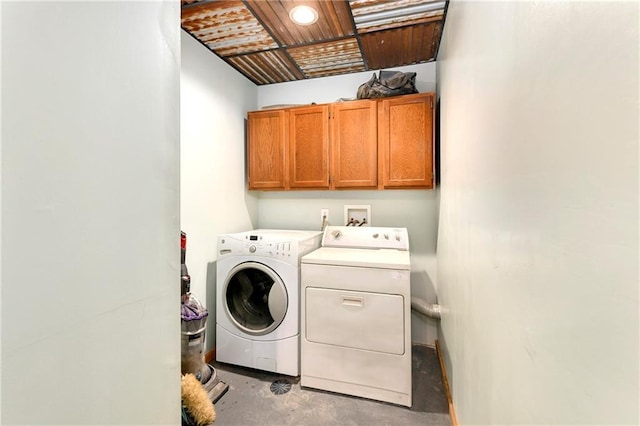 clothes washing area featuring cabinets and separate washer and dryer