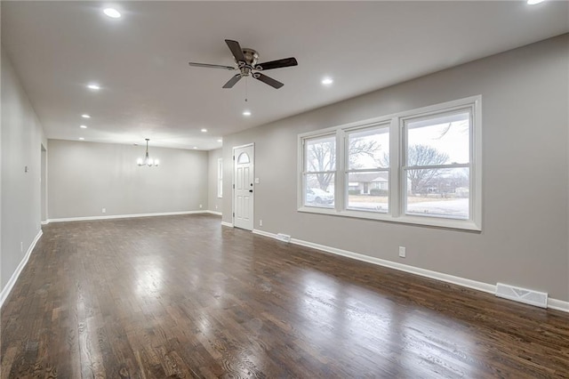 unfurnished living room featuring ceiling fan with notable chandelier and dark hardwood / wood-style flooring