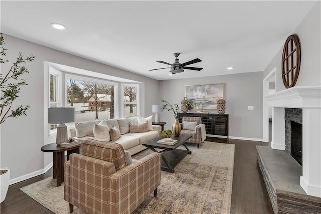 living area with a fireplace with raised hearth, dark wood-style floors, and baseboards