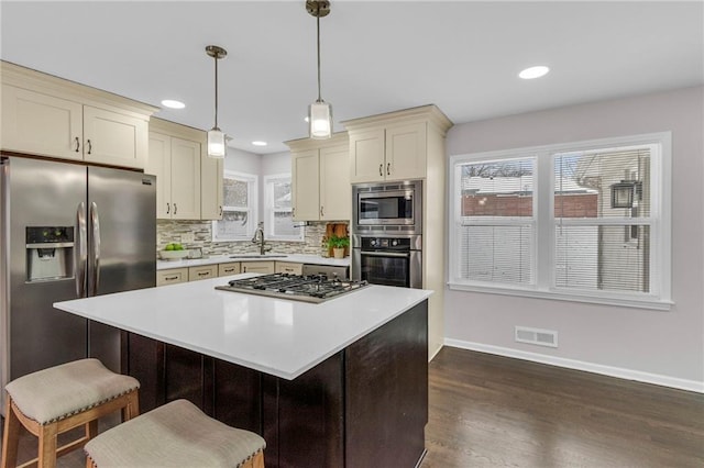 kitchen featuring dark wood-style flooring, light countertops, visible vents, decorative backsplash, and appliances with stainless steel finishes