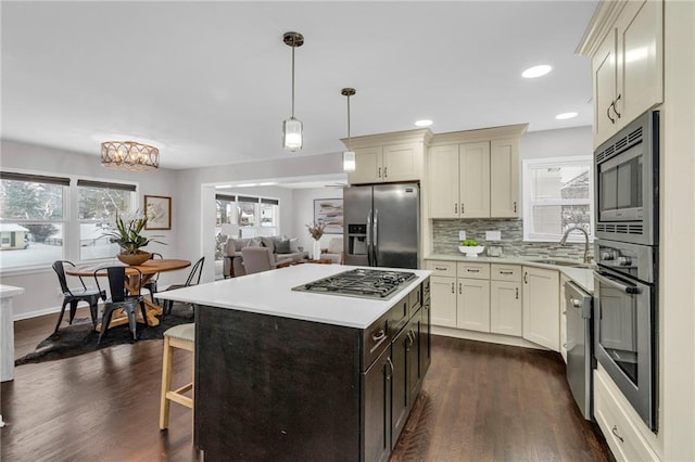 kitchen with stainless steel appliances, dark wood-style flooring, a sink, light countertops, and decorative backsplash