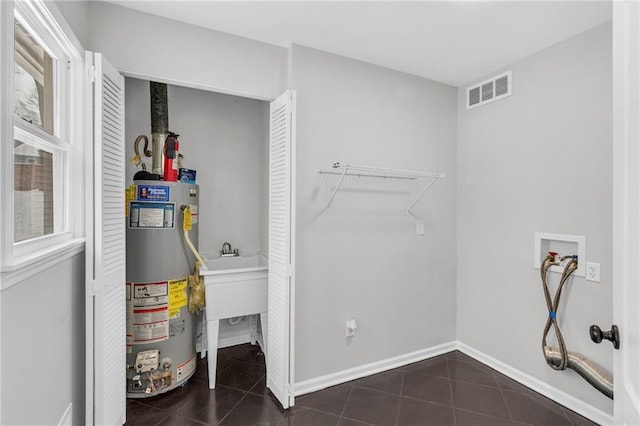 laundry area with laundry area, visible vents, dark tile patterned floors, water heater, and washer hookup