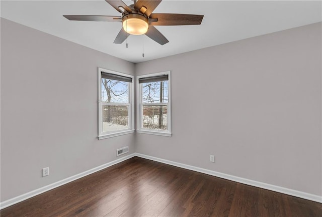 spare room with dark wood-type flooring, visible vents, baseboards, and a ceiling fan