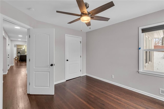 unfurnished bedroom with stainless steel fridge, visible vents, baseboards, ceiling fan, and wood finished floors