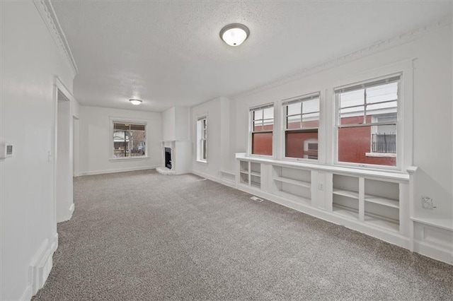 unfurnished living room featuring crown molding, carpet flooring, and a textured ceiling