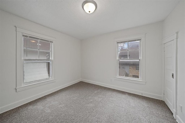 spare room featuring a textured ceiling and carpet