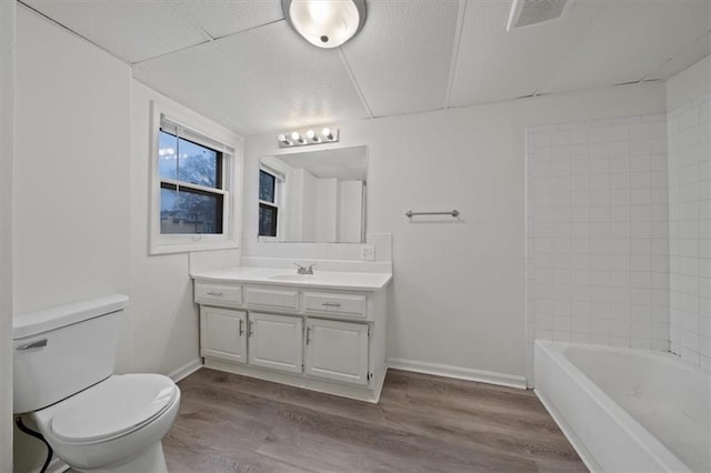 full bathroom featuring hardwood / wood-style flooring, vanity, tiled shower / bath, and toilet