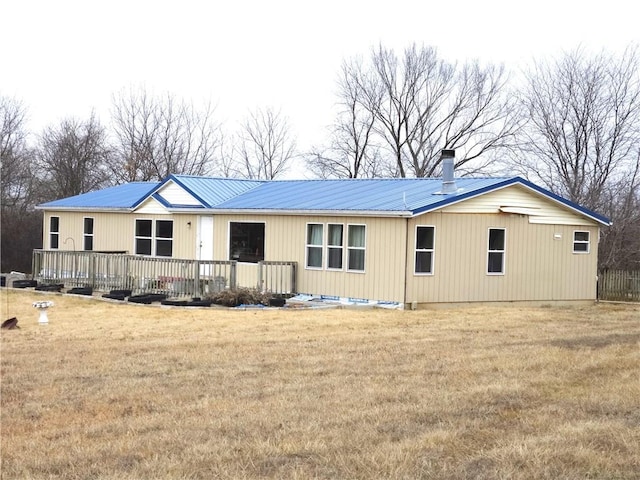 rear view of house with a wooden deck and a lawn