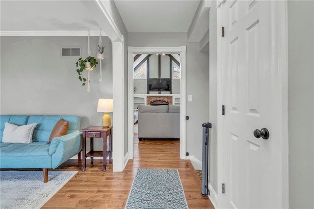 hallway featuring light wood-type flooring, visible vents, and baseboards