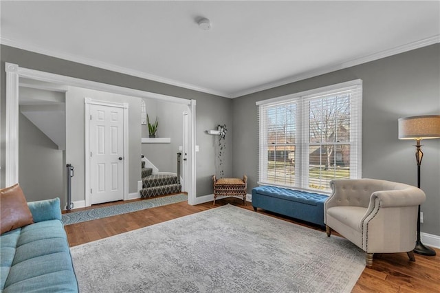 living area with stairway, crown molding, baseboards, and wood finished floors